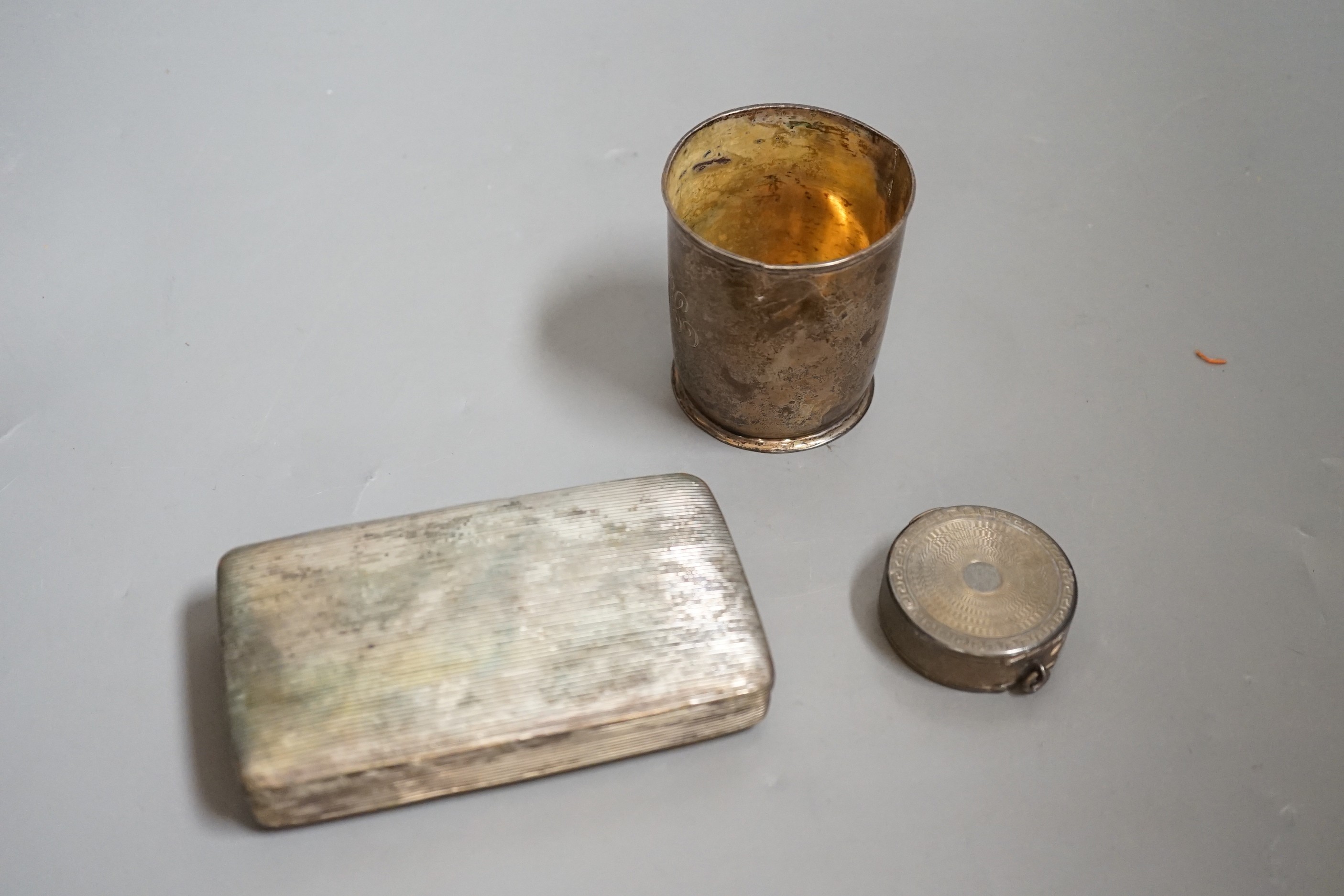 A Dutch white metal tobacco box, 11.3cm and a similar beaker (both a.f.) together with a French engine turned white metal circular compact.